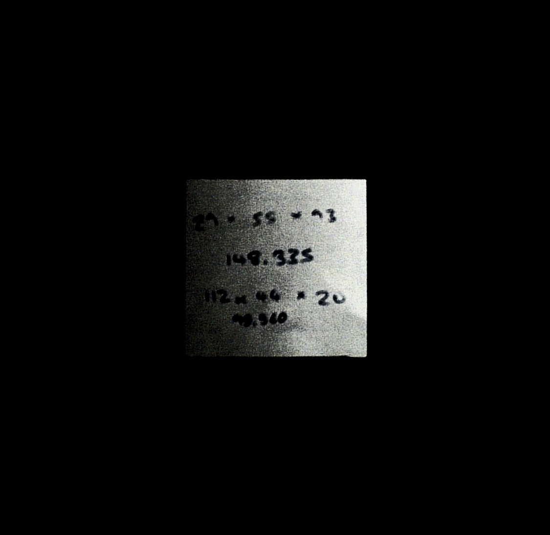 A black square. In the central ninth there's a sticky note, square with slightly irregular edges, and a small notch near the right end of the bottom edge. It bears text written roughly in thick black marker pen, not clearly distinguishable, centred over 4 lines: “29 × 55 × 93” / “148.335” / “112 × 44 × 20” / “98.560”. The note appears white, grainy, dithered from almost-all bright white at the right, to almost black at the left.